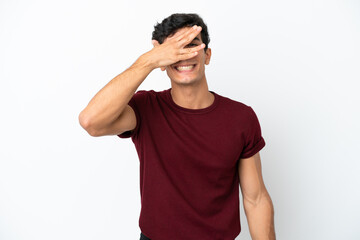 Young Argentinian man isolated on white background covering eyes by hands and smiling