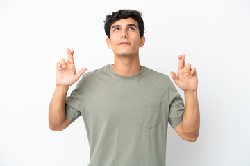 Young Argentinian man isolated on white background with fingers crossing and wishing the best