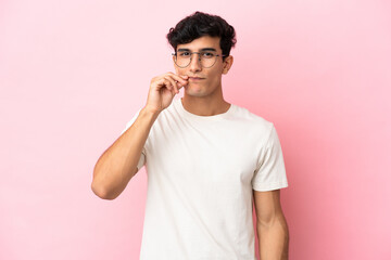 Young Argentinian man isolated on pink background showing a sign of silence gesture