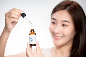close up asian woman looks at a bottle of CBD oil. Sleep supplement. Medical marijuana. vitamins and supplements healthy alternatives..
