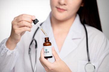 close up Medical technologist asian woman looks at a bottle of CBD oil. Research on cannabis extracts. Sleep supplement. Medical marijuana. vitamins and supplements healthy alternatives.