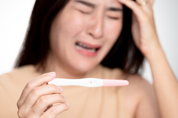 Asian woman holding pregnancy test feeling disappointed by negative result female health problems and infertility. or unwilling pregnancy, abortion.