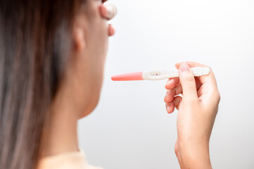 Asian woman holding pregnancy test feeling disappointed by negative result female health problems...