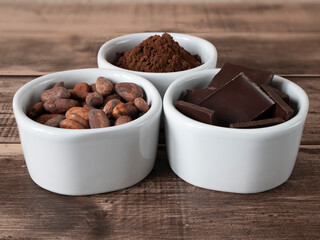 Chocolate chunks, cocoa powder and beans - products for confectionery. Three bowls with ingredients full of antioxidants