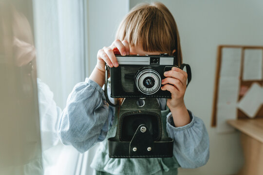 Unrecognizable little girl taking photo by film camera