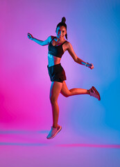 Fototapeta na wymiar Athlete asian sportswoman jumping as part of fat burning workout in fitness studio neon background. Woman exercising with cardio at the gym.