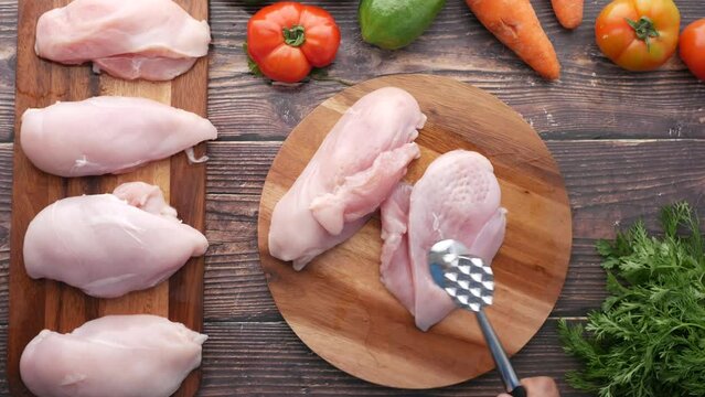 precessing raw chicken breast on a chopping board 