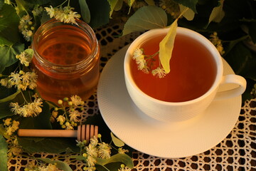 jar of linden honey with linden blossom and cup of tea