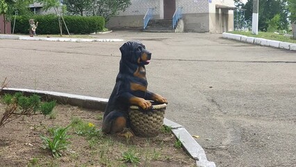 Artificial figurine of a dog with a basket in the yard in summer