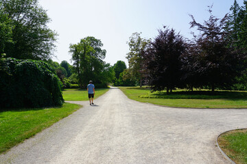 Ein Mann geht im Kurpark in Bad Pyrmont spazieren an einem sonnigen Tag 