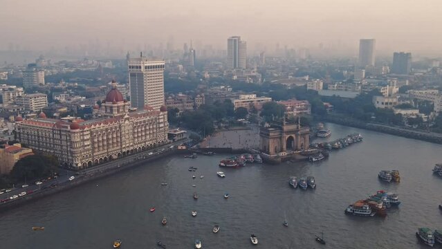 Aerial view of Gateway of India. Cityscape of old Mumbai town. Early morning weather on the seashore of Mumbai. Drone view of Taj Palace Hotel. Fishings boats sail in the sea during sunrise.