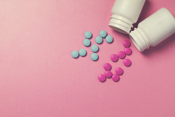 Blue and pink pills spill out of white jars
