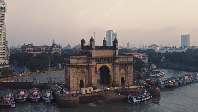 Aerial view of Gateway of India. Cityscape of old Mumbai town. Early morning weather on the seashore of Mumbai. Drone view of Taj Palace Hotel. Fishings boats sail in the sea during sunrise.
