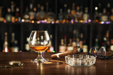 Closed up view of glass of cognac with cigar on color back