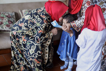Grandmother kissing her grandchild while giving money during Idul Fitri day. Indonesian people tradition during Eid Mubarak celebration of distributing money or called THR. 