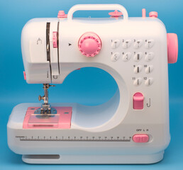 Máquina de coser de color blanco, detalles en rosa, sobre fondo de color azul 