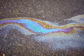 Oil stain on the asphalt, rainbow-shaped colored gasoline stains on an asphalt road as a texture or background