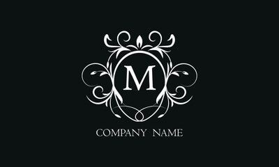 Elegant floral monogram with decorative elements and the letter M. Template for invitations, labels, business. Wedding monograms. Exquisite calligraphic ornament.