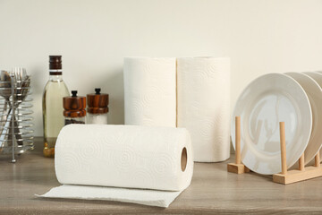Many rolls of white paper towels and other kitchen stuff on wooden countertop near light wall
