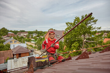 Rope access. Roof repair, the Installer installs snow retention on the roof of the cottage.