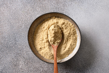 Sesame flour in bowl on gray background. Cooking gluten-free and low carbohydrate dessert. Good source of protein. View from above.