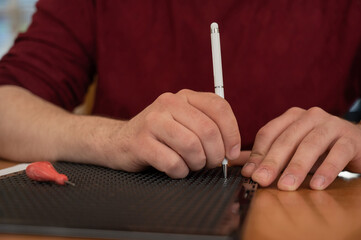 A man uses a special stylus to write a letter in braille. 