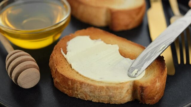 Spreading Butter On Bread with knife, close up. Soft butter spreading on slice of sourdough bread