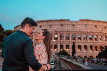 portrait of a couple in love in front of the roman colosseum - obrazy, fototapety, plakaty