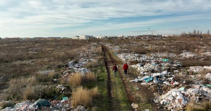 two people walking on a huge aste, garbade, dump, rubbish landill in Bucharest