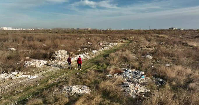 two people walking on a huge aste, garbade, dump, rubbish landill in Bucharest