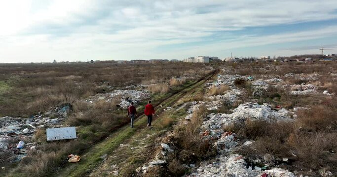 two people walking on a huge aste, garbade, dump, rubbish landill in Bucharest
