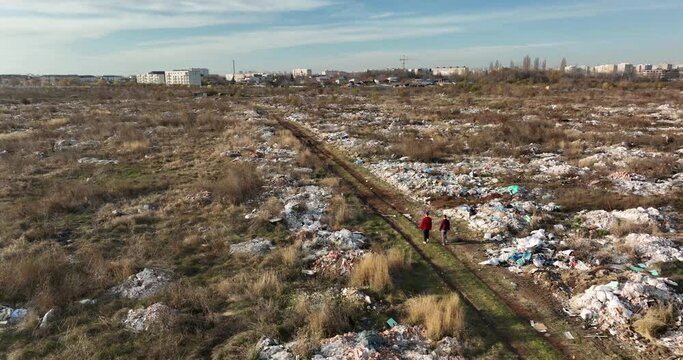 two people walking on a huge aste, garbade, dump, rubbish landill in Bucharest