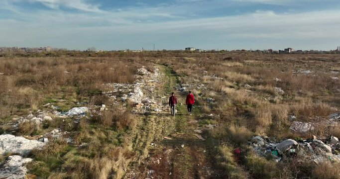 two people walking on a huge aste, garbade, dump, rubbish landill in Bucharest