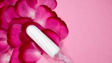 Flat lay, tampon and pink petals of rose flower. Menstruation and women's health concept. Copy space or negative space.