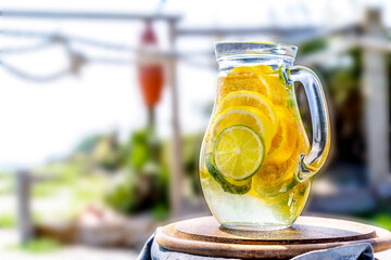 Detox infused water with lime, lemone, oranges, mint in jar and with sea coast view
