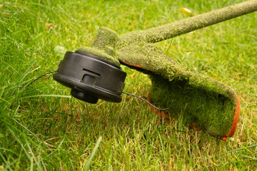 Petrol trimmer mows green grass. Photography with movement