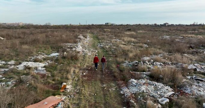two people walking on a huge aste, garbade, dump, rubbish landill in Bucharest