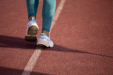 Detalle de pies de mujer corriendo en una pista atlética. Concepto de deportes y gente.