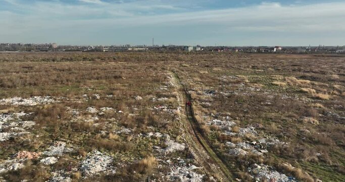 two people walking on a huge aste, garbade, dump, rubbish landill in Bucharest