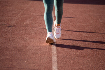 Detalle de pies de mujer corriendo en una pista atlética. Concepto de deportes y gente.