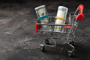 Shopping cart with dollar banknotes on a black background.Business finance shopping concept.Saving...