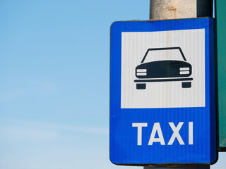 Blue taxi sign station against blue sky.