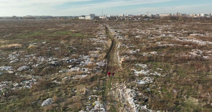 two people walking on a huge aste, garbade, dump, rubbish landill in Bucharest
