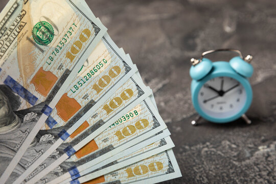 Blue alarm clock on money banknotes Dollars, business planning and finance concept.Time is money.Finance and economics concepts. Money accumulation concept. Saving currency. Investments. Copy space.