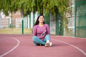 Mujer deportista sentada en una pista atlética. Concepto de personas y estilo de vida.