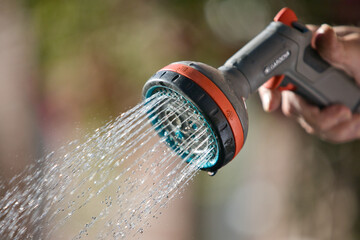 Close-up shot of watering plants with a garden hose and a handheld sprayer in the evening