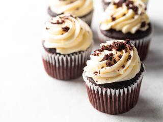 Chocolate muffins with whipped cream, decorated with chocolate chips. Isolated on white background. Celebration of birthday, anniversary. Banquet, picnic, restaurant, confectionery.