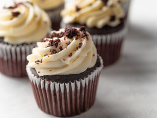 Close-up. Chocolate muffins with whipped cream and garnished with grated chocolate on a white background. Large group of objects. Restaurant, hotel, confectionery, cafe.