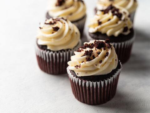 Appetizing chocolate cupcakes with cream and chocolate chips on a white background. There are no people in the photo. Sweet food. Delicious dessert. Banner, advertising.