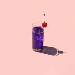 Colorful cocktail with cherry on pastel light pink background. Creative drink concept. Minimalistic beverage composition.